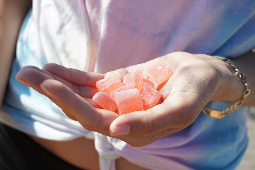 A hand holding several pink CBD gummies outdoors, highlighting their potential benefits for gut health.